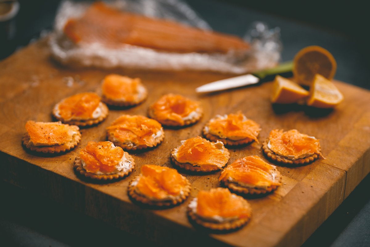 salmon and cheese on crackers on a wooden chopping board