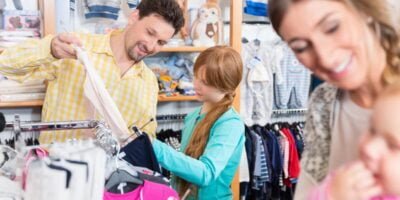 Father looking clothes on rail for sensory friendly clothing with daughter in shop