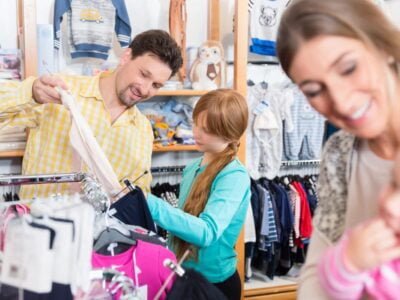 Father looking clothes on rail for sensory friendly clothing with daughter in shop