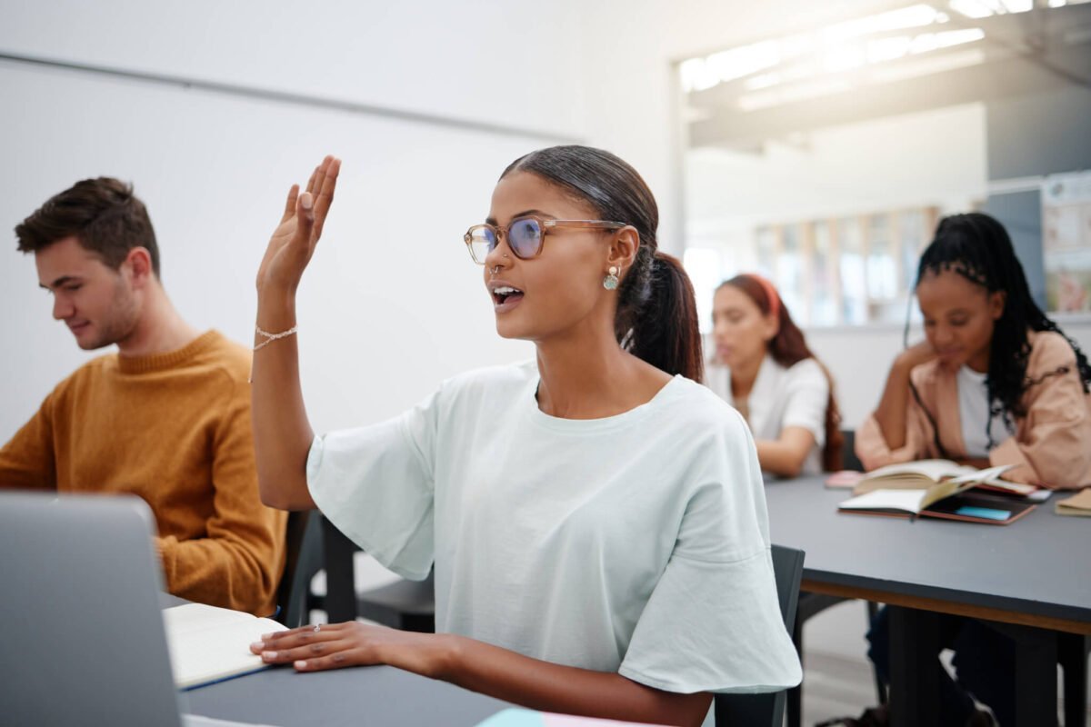 Lady with glasses putting her hands up in university classroom