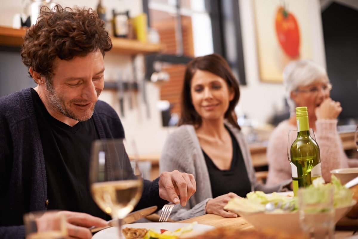Man eating at dinner table engaging in socially awkward conversation