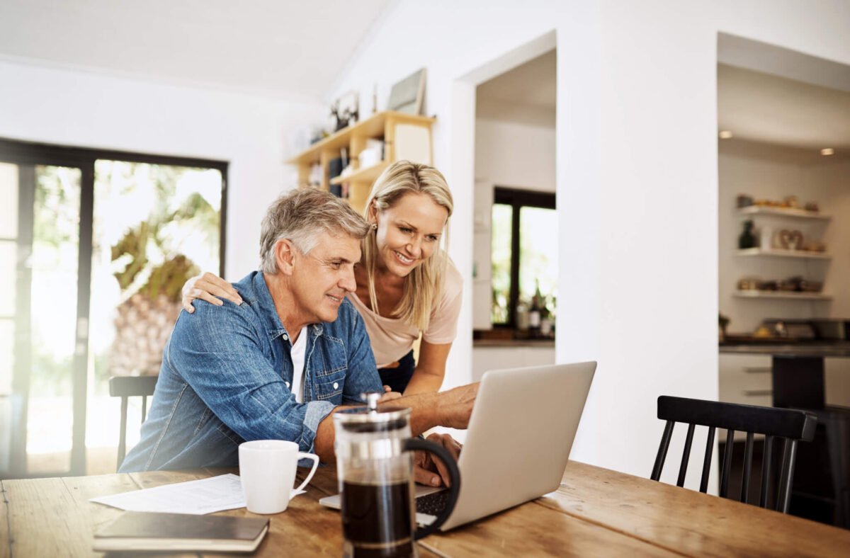 old couple smiling at computer while doing finances