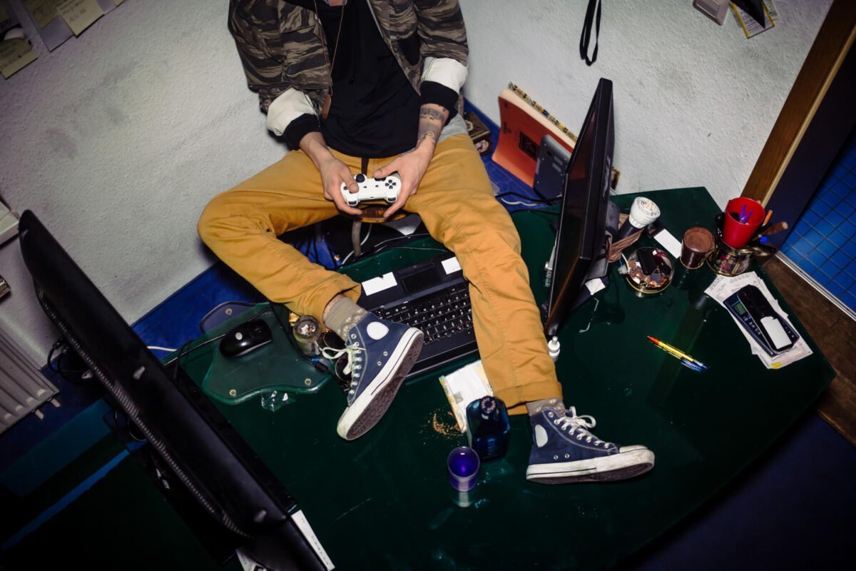 teenager playing video games on messy desk