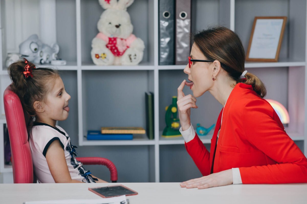speech and language therapy session with young girl and therapist in red jacket