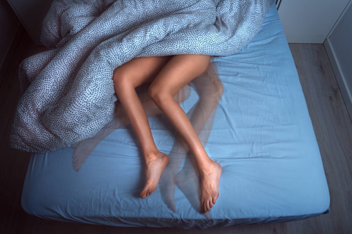 woman with restless legs sleeping on a blue bed