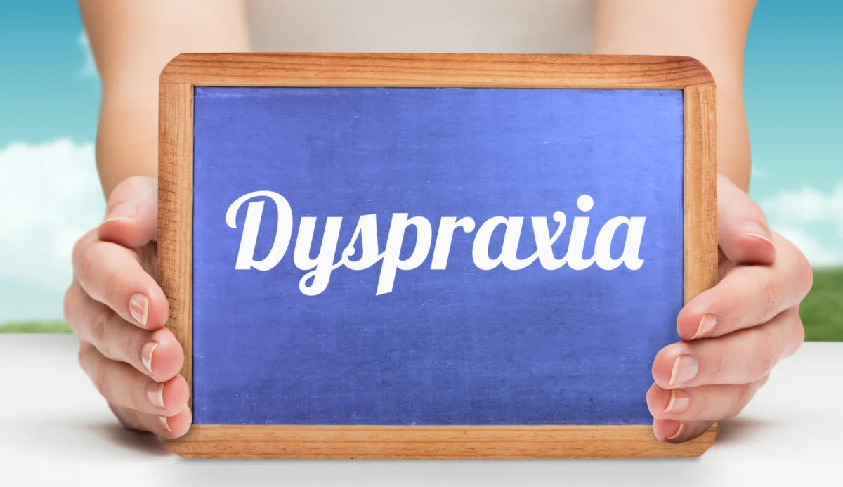The word dyspraxia and hands showing chalkboard against field and sky