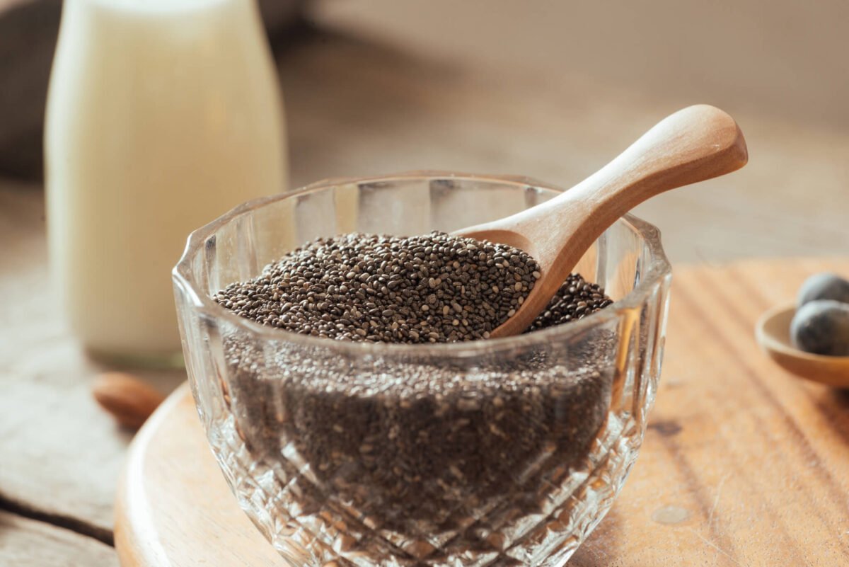 chia seeds in a bowl with wooden spoon and milk in background