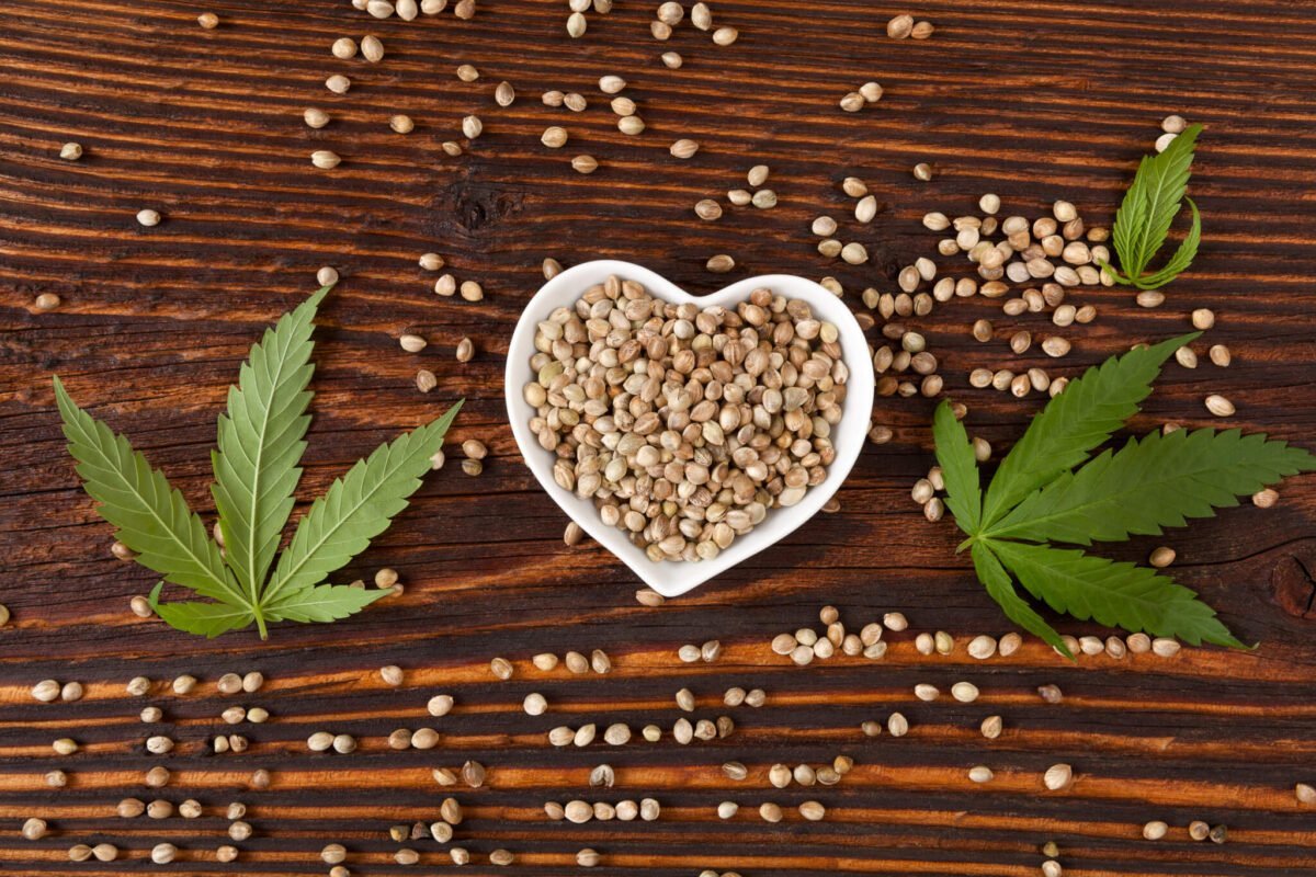 hemp seeds in a love heart shaped bowl with hemp leaves surrounding