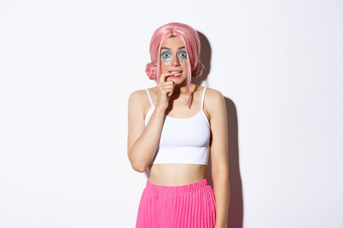 Young girl with pink hear and heavy quirky blue makeup looking anxious