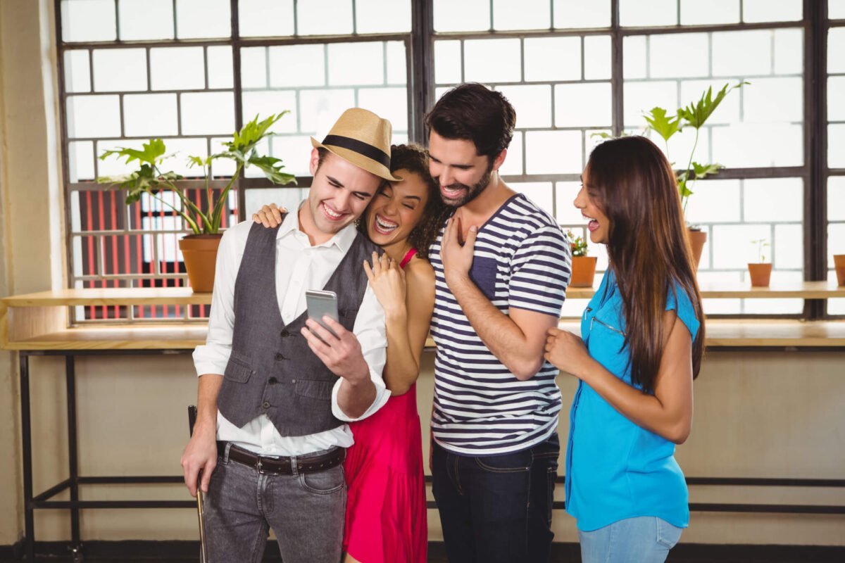 group of young adults smiling around a mobile phone