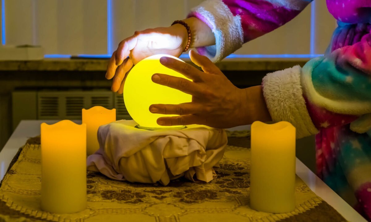 crystal ball surrounded by candles and fortune teller hands