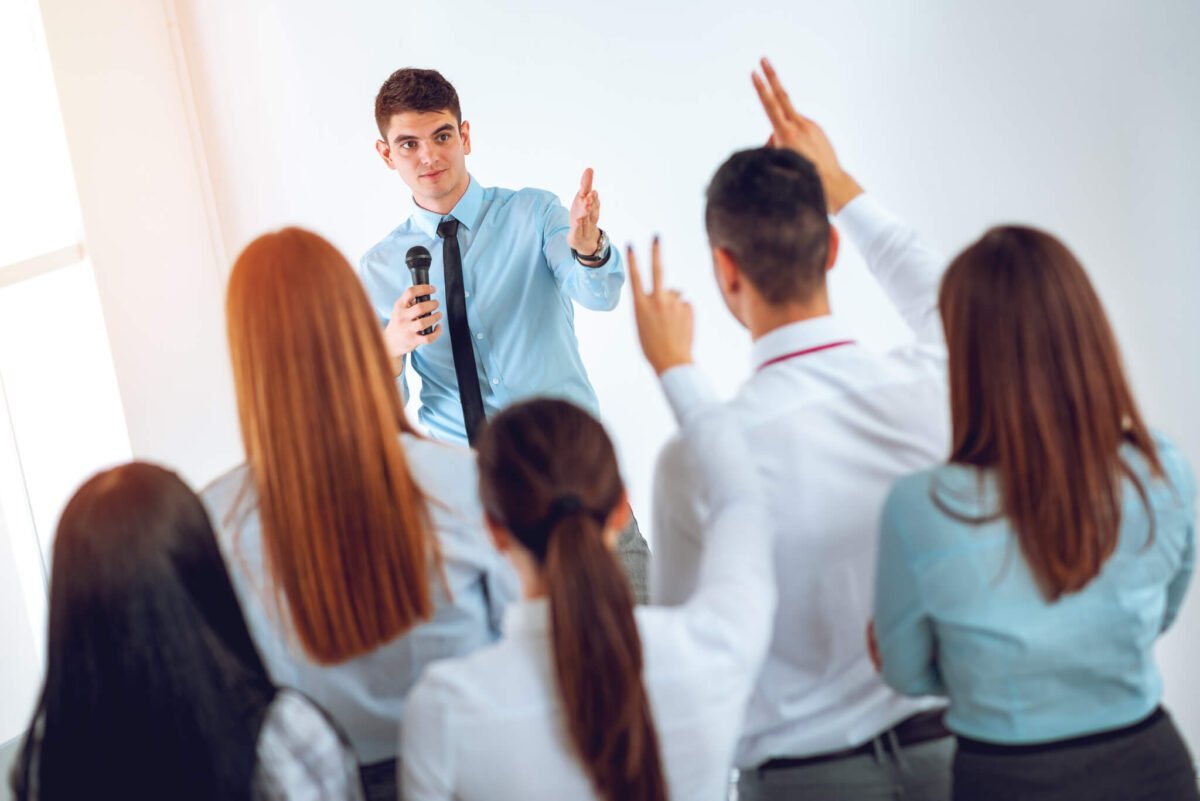 business men and women in a q and a session in a small white room.