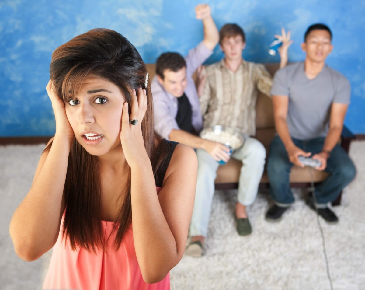 young girl overwhelmed by loud noises of men playing games in background