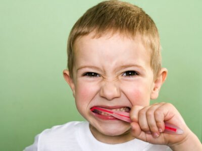 autistic child brushing his teeth with three-sided toothbrush