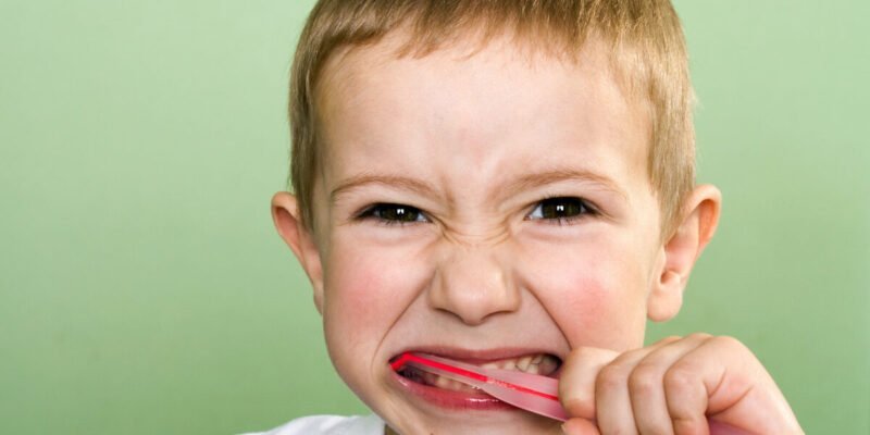 autistic child brushing his teeth with three-sided toothbrush