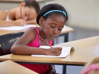 Black Girl in Classroom Writing while Making Vocal Stimming noise