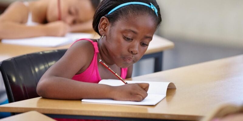 Black Girl in Classroom Writing while Making Vocal Stimming noise