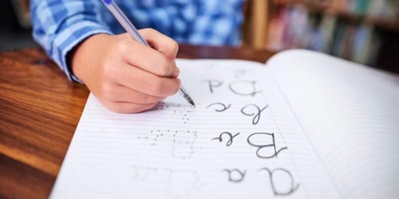Shot of an unrecognisable young boy writing in a book at school.