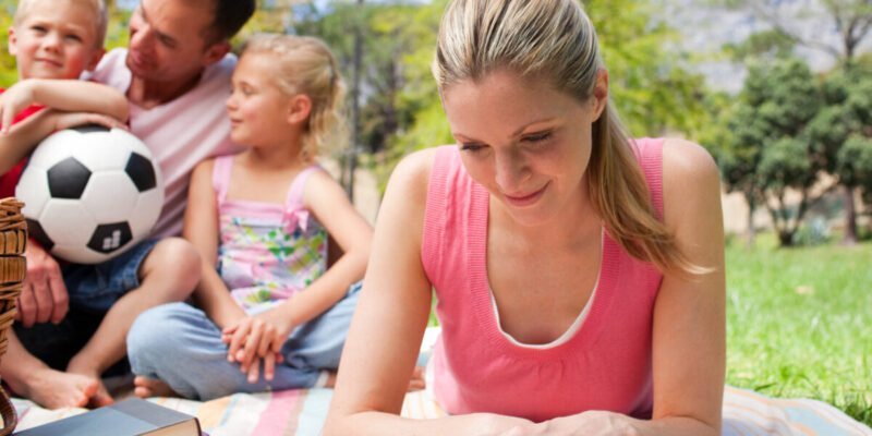 Concentrated mother reading at a picnic with her family