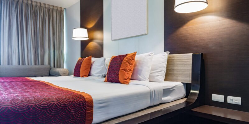 Red pillow on double bedroom with white compression bedsheet and lamp light