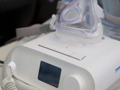 A machine for sleep apnea sits ready for use by someone who snores