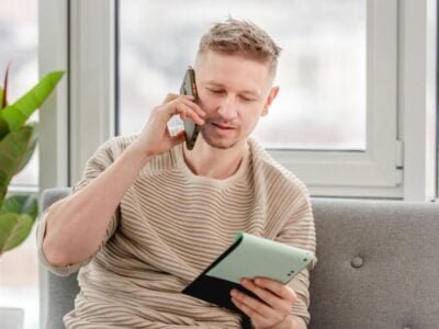 Autistic freelancer businessman talking by phone and holding notepad in his hands. Remote distance work at home during Covid pandemy