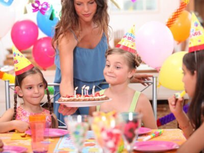 young girl about to blow out candles on birthday cake at a birthday party with neurodivergent parent