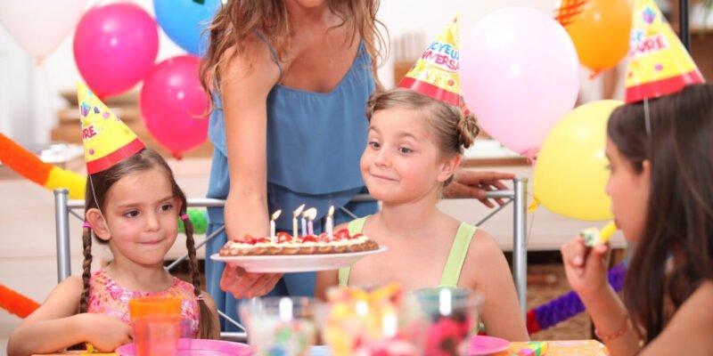 young girl about to blow out candles on birthday cake at a birthday party with neurodivergent parent