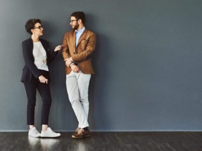 Shot of two designers having a conversation while leaning against a wall
