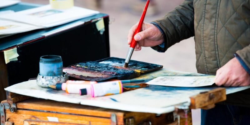 Painter with brush painting his picture on a street