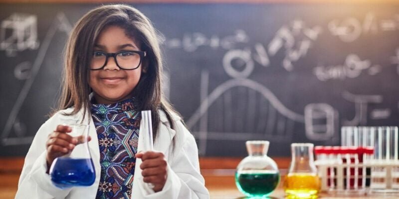 a cute little girl in a science lab smiling at camera in lab coat and her splinter skill is science
