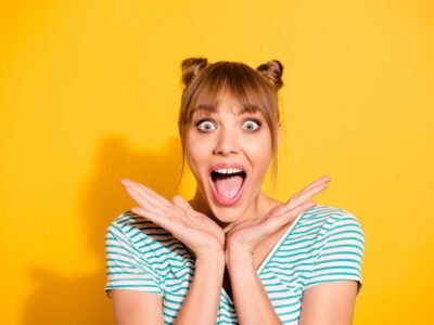 close up of beautiful girl with tooth gap smiling and hands up to her chin in excitement